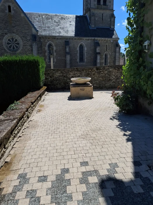 Cour pavée devant église romane en pierre avec tour clocher