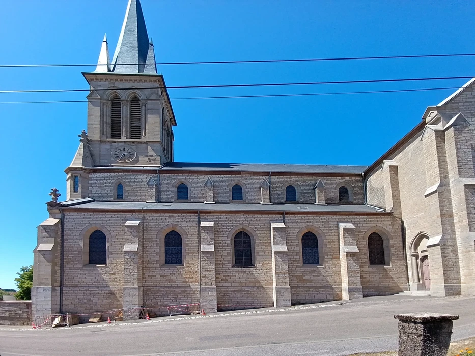 Église en pierre de style roman avec clocher carré, située en milieu urbain