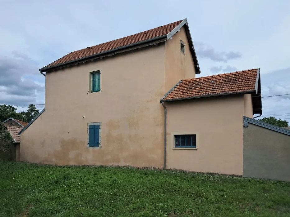 Maison individuelle de plain-pied avec combles aménagés, façade crépi beige, volets battants marron